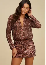 Vestido corto de estilo camisero con estampado animal print, confeccionado en tela fluida. Presenta cuello camisero, cierre frontal con botones, mangas largas con puños abotonados y una falda recta.