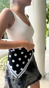 Pañuelo cuadrado de tela sintética color negro con lunares blancos y borde blanco.