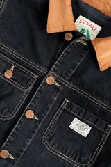 Campera corta de jean negro con cuello de pana marrón, confeccionada en jean grueso 100% algodón de 14 onzas, con costuras marrones en contraste.