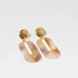 Par de aros colgantes con base dorada y dije con forma geométrica irregular en tonos beige, marrón y blanco.