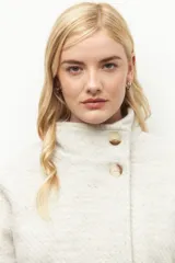 Tapado corto color beige de tejido grueso con cuello alto, cierre frontal con botones grandes veteados y bolsillos delanteros.