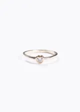 Anillo dorado con zirconia transparente en forma de corazón.