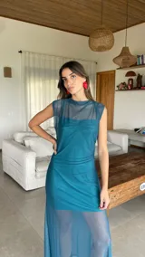 Vestido largo de microtul bordó, sin mangas, con escote alto tipo buche y diseño transparente con forro corto interno que genera un efecto translúcido en la falda.