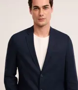 Saco de traje masculino confeccionado en mezcla de lino y viscosa, con cierre frontal de dos botones, bolsillos laterales con solapa y medio forro interior.