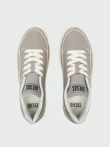 Zapatillas Diesel modelo S-Tracker-D, estilo retro de caña baja, color gris con cordones blancos y suela gruesa color crema. Presentan texturas en el material exterior y el logo de la marca en el lateral.