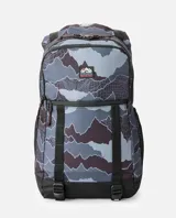 Mochila Rip Curl modelo Dawn Patrol 30L Search, de diseño estampado tipo camuflado en tonos gris, azul y negro. Cuenta con compartimento principal tipo rollo, bolsillos frontales con cierre, bolsillo lateral de malla para botella, correas ajustables y base negra reforzada.