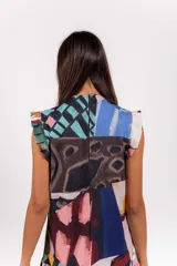 Vestido largo sin mangas de cuello alto, con estampa abstracta multicolor, volados en las mangas y falda con volado inferior.