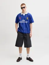 Camiseta de estilo polo con cuello camisero, manga corta y calce relajado. Presenta un diseño en color azul con estampado frontal "FIFA WORLD CUP" y detalles gráficos en contraste. Confeccionada en tejido técnico de poliéster reciclado.