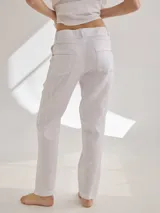 Pantalon de lino color blanco, de corte recto y tiro medio. Presenta costuras decorativas visibles, bolsillos laterales y cierre frontal con botón.