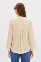 Blusa blanca de viscosa con detalles de broderie en los hombros, cuello en V y mangas largas holgadas.