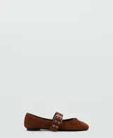Zapatos planos de gamuza marrón, con punta fina, cierre de dos tiras con hebillas metálicas en el empeine y detalle de lazo pequeño en la puntera.