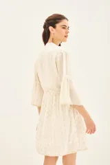 Vestido corto blanco con estampado de puntos dorados, mangas al codo con volados y ajuste en la cintura. Escote en V con detalles bordados en dorado y negro.
