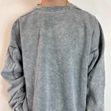 Buzo de cuello redondo con corte oversize, confeccionado en tela con efecto lavado ácido. Presenta costuras reforzadas visibles y una pequeña etiqueta con logo en el puño.