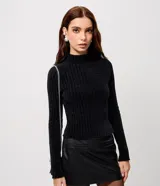 Blusa cropped de punto chenille color negro, con cuello alto y mangas largas raglán. Presenta una textura acanalada y pequeños puntos brillantes aplicados en el frente.