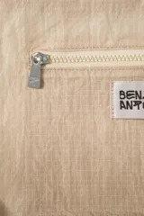 Bolso de hombro de tejido color beige, con diseño tipo medialuna, asa larga y cierre de cremallera.