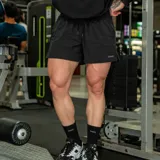 Short deportivo negro de tejido técnico tipo nylon, liviano y de secado rápido, con cintura elastizada, cordón regulable y bolsillos laterales. Cuenta con pequeños tajos laterales en el ruedo y el logo de la marca estampado en el lateral.