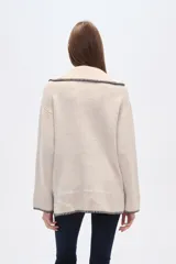 Sweater negro holgado con cuello en V y ribete en color crema en cuello, puños y ruedo.