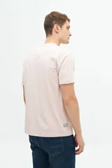 Remera de manga corta color rosado, con estampado frontal de hojas en tonos azules y texto "Organiquis Les Formes" y "Bisfield Est. 1971".