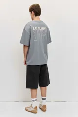 Remera blanca de manga corta, corte oversize, con estampa en la espalda de una flor sobre fondo difuminado verde y blanco.