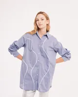Camisa celeste de algodón con corte oversized, botones frontales a tono y vivos blancos ondulados en el frente.