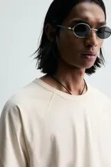 Camiseta relaxed fit color gris oscuro, confeccionada en tejido ligero de algodón con elasticidad. Presenta cuello redondo y manga ranglán corta.