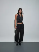 Pantalón negro de encaje con transparencias, tiro medio y cintura elástica ajustable con cordón.