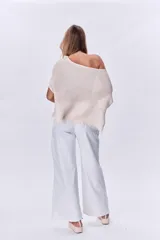 Poncho de tejido de punto color beige, con cuello amplio y terminación con flecos.