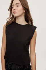 Remera sin mangas negra con cuello redondo y hombros estructurados con hombreras, de corte recto y largo a la cintura.