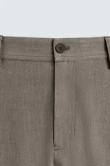 Pantalón chino de corte slim fit, confeccionado en tejido elástico. Presenta bolsillos frontales, bolsillos traseros de vivo con botón y cierre frontal con cremallera y botón.
