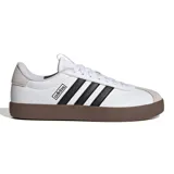 Championes Adidas modelo VL Court 3.0 para mujer, de color blanco con detalles en negro y suela de goma marrón. Presentan un diseño de corte bajo con las tres tiras clásicas de la marca en los laterales y puntera de gamuza en tono gris claro.