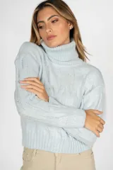 Sweater de punto color celeste con cuello alto y diseño de trenzas verticales. Presenta puños y ruedo acanalados.