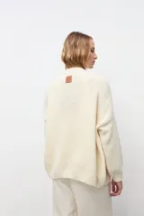 Cardigan abierto de punto color crudo, con mangas largas y corte holgado.