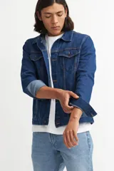 Campera de jean celeste con cuello clásico, cierre frontal con botones metálicos negros, bolsillos con solapa abotonada en el pecho y mangas largas con puños abotonados.