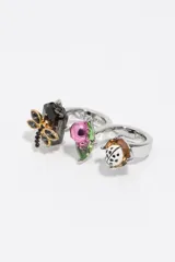 Anillo doble de metal plateado con diseño decorativo de insectos, incluyendo una libélula con cristales oscuros, un escarabajo rosa sobre una hoja verde y una mariquita esmaltada.