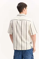 Camisa de manga corta oversize en tejido rústico, con diseño de rayas verticales celestes y blancas, cuello clásico y cierre frontal de botones.