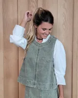 Chaleco de corte recto y largo a la cintura, confeccionado en denim con estampado de rayas verticales en tonos azul y blanco. Presenta cuello redondo y costuras visibles que definen su estructura.