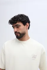 Remera de manga corta color verde militar con textura sutil y pequeña estampa discreta en el pecho.