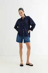 Camisa color beige de corte amplio, con cuello clásico, manga larga y bolsillo en el pecho.