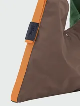 Bolso tipo hobo de gran tamaño en color verde, con detalles laterales en naranja y correa de hombro integrada. Presenta un diseño minimalista con cierre de botón a presión.