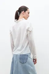 Camisa blanca de manga larga con cuello mao y puntilla calada en el frente y puños.