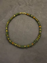 Collar corto de piedras volcánicas negras en la base del cuello, con pequeños detalles en tonos tostados y dorados.