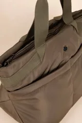 Bolso tipo shopper color beige, con asas fijas superiores y correa desmontable y regulable. Cuenta con dos bolsillos externos y tres bolsillos internos.