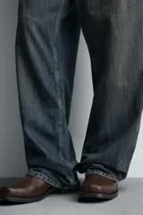 Bota de media caña con detalle de pespunte en la parte superior, cierre mediante cremallera lateral, horma cuadrada y suela a tono con ligero tacón.