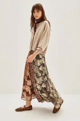 Falda larga plisada con diseño patchwork de diferentes estampados florales y abstractos en tonos otoñales y oscuros, con detalles metalizados. El forro es de poliéster.