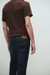 Jeans de tiro medio, corte regular, color azul oscuro, con lavado stone wash y bigotes láser.