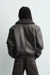 Cazadora de corte relajado confeccionada en tejido efecto piel, con cuello de solapa de pelo sintético desmontable, cierre frontal de cremallera oculta por solapa con botones a presión, bolsillos laterales y puños y bajo en rib.