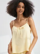 Musculosa color amarillo pastel, con tirantes finos y escote en V con lazo decorativo.