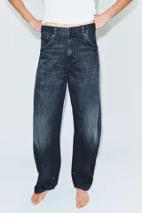 Jeans de tiro medio con diseño tipo balloon, cinco bolsillos y bajo ajustable con trabilla y botones. Cierre frontal con cremallera y botón metálico.