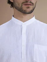 Camisa blanca de manga larga con cuello mao y cierre frontal de botones.