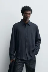 Camisa de corte relajado confeccionada en tejido fluido con mezcla de viscosa. Presenta cuello solapa, cierre frontal con botones y manga larga con puños abotonados.